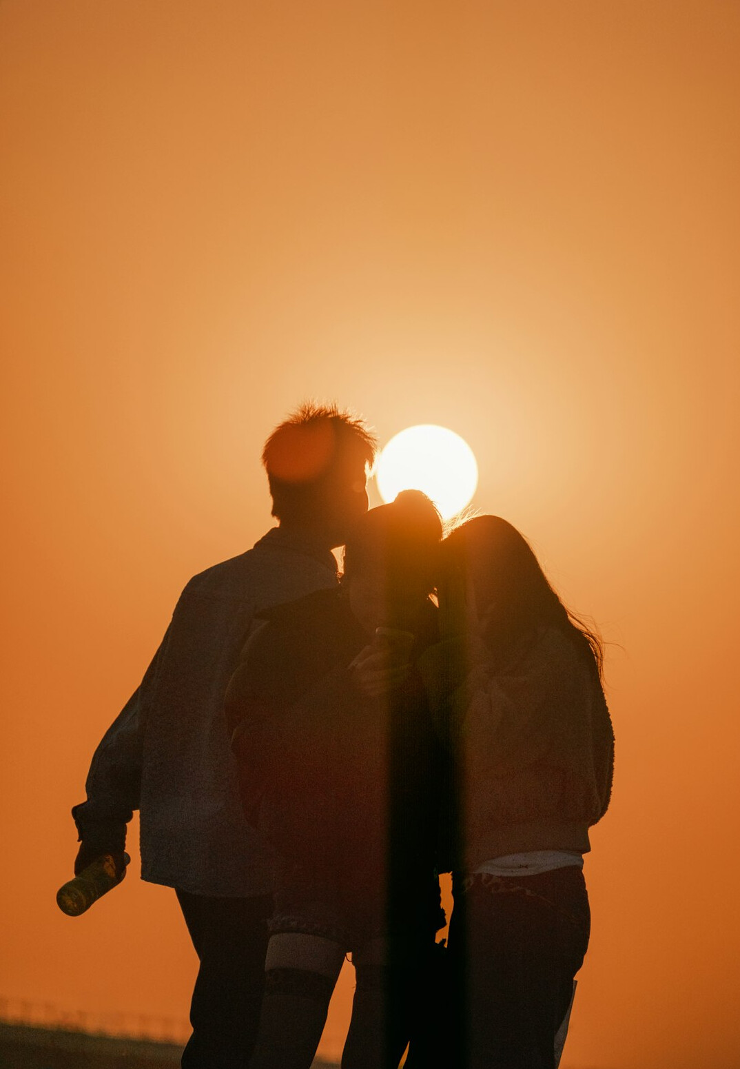 Group of young people embracing outdoors at sunset